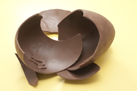 Pieces of a chocolate Easter Egg photographed over yellow.